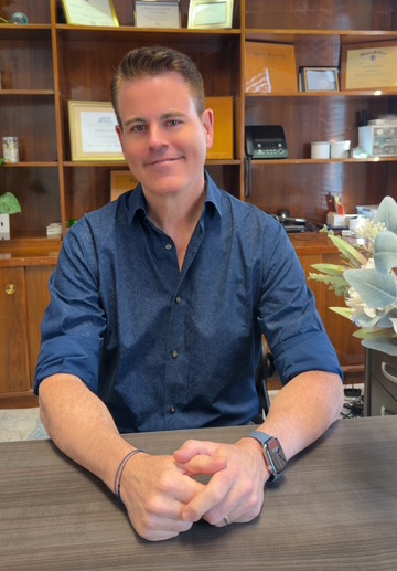 Jake Marsden, Au.D., Doctor of Audiology at Manhattan Audio, smiling in the office.