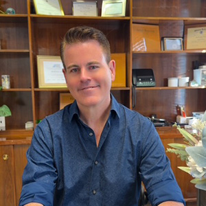 Jake Marsden, Au.D., Doctor of Audiology at Manhattan Audio, smiling in the office.